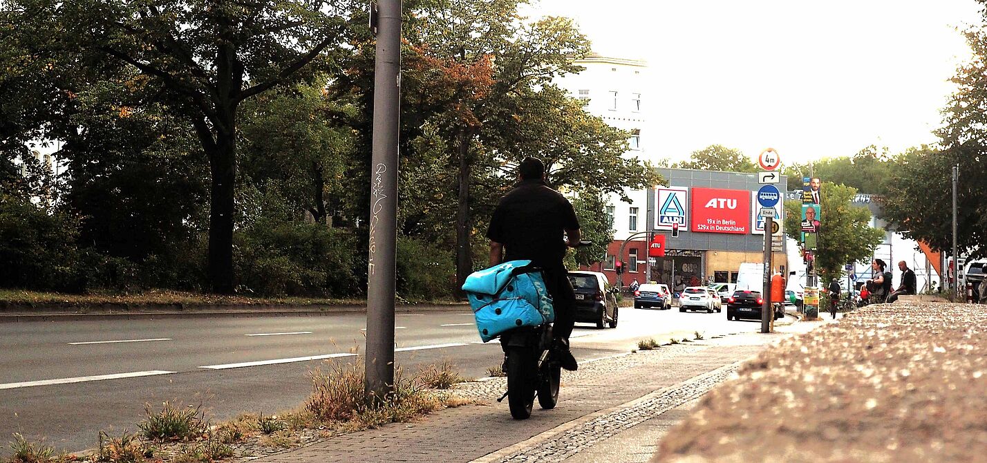 Lieferdienst-Fahrer auf dem Fahrrad transportiert eine Wolt-Transport-Box auf dem Gepäckträger