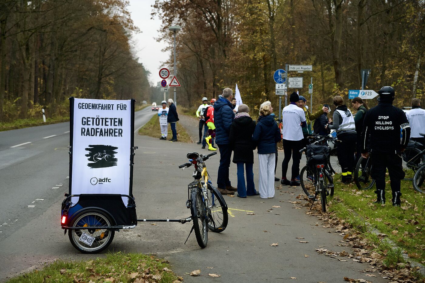 #VisionZero-Demo und Mahnwache für getöteten Radfahrer in Müggelheim Menschen stehen für eine Mahnwache auf der Straße, Vision Zero Transparent im Vordergrund