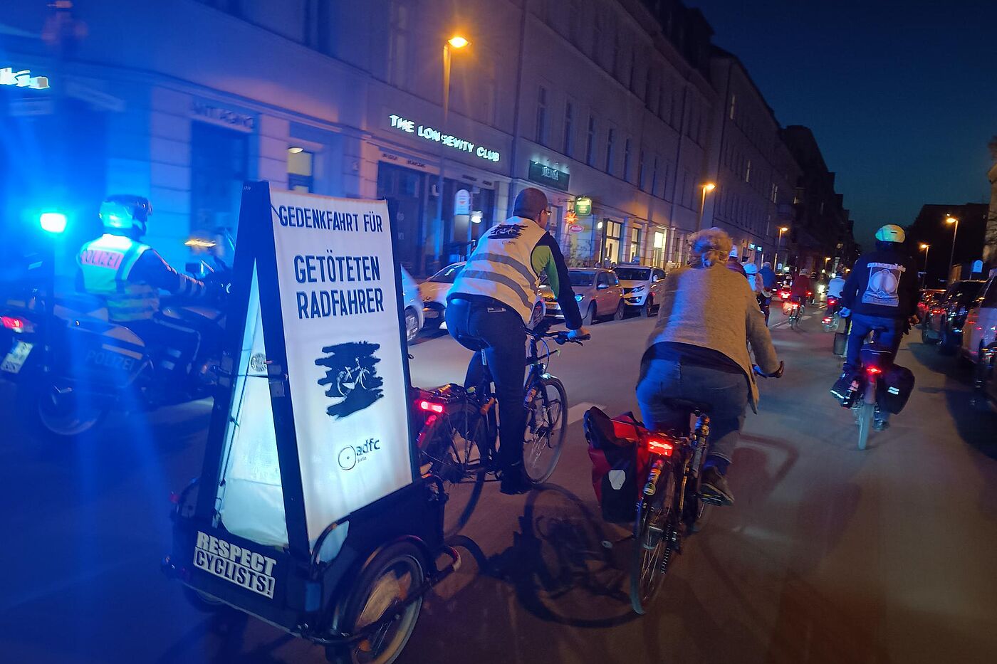 Demo Geisterrad Neukölln März 2025 Radfahrende im Dunkeln mit leuchtenden Schild auf dem "Gedenkfahrt für getöteten Radfahrer" steht