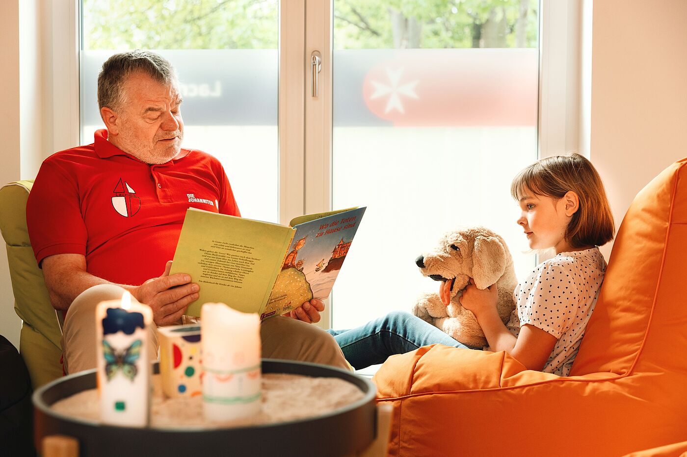 Ein Mann liest einem Mädchen mit einem Stofftier ein Buch vor