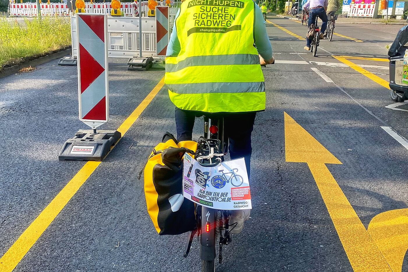 "Suche sicheren Radweg!" Mit Changing Cities auf der Filandastraße Eine Frau fährt mit dem Fahrrad in einer Demo auf der Filandastraße. Sie trägt eine gelbe Weste mit der Aufschrift "Suche sicheren Radweg" von Changing Cities