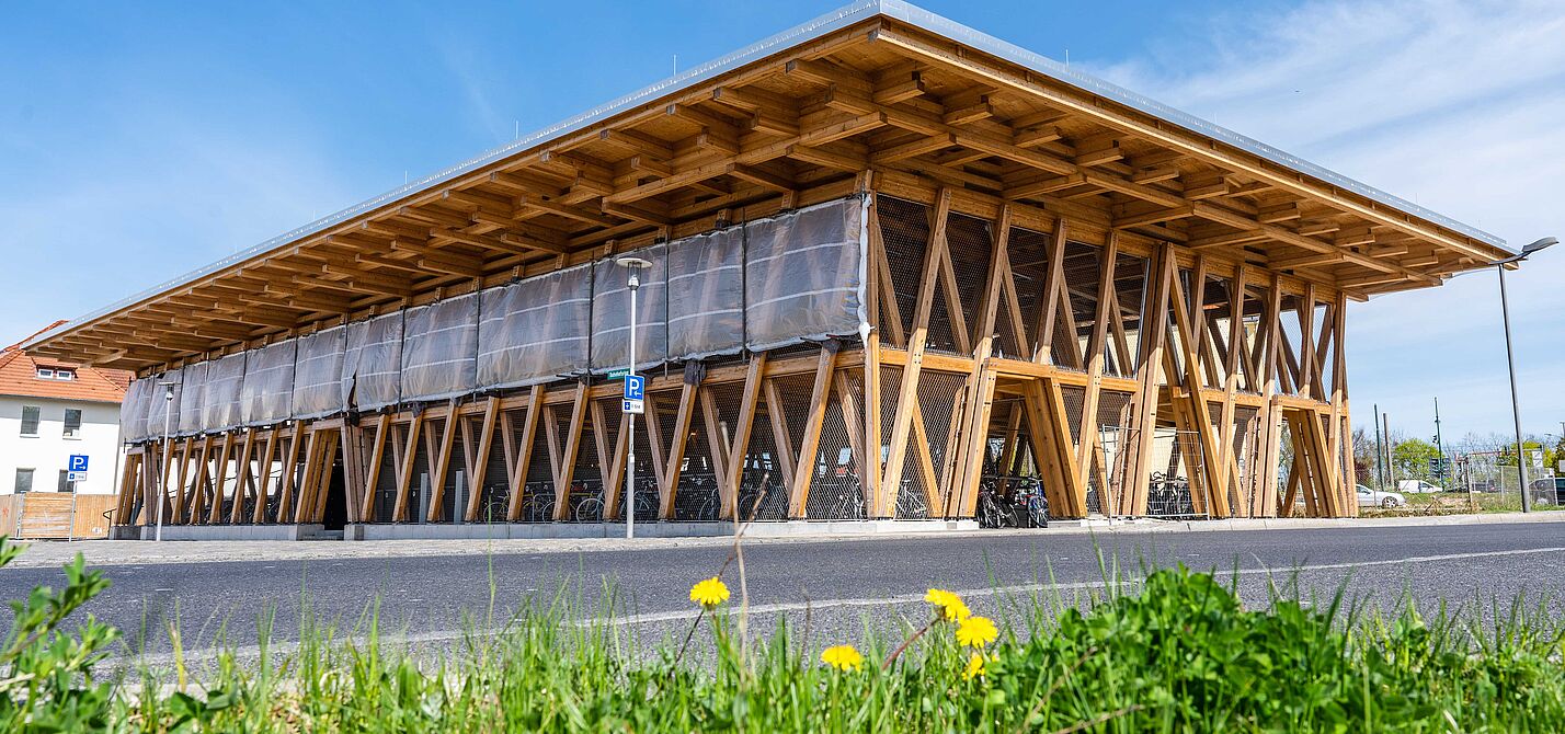 Fahrradparkhaus Eberswald Eine Fahrradparkhaus in Holzkonstruktion vor blauem Himmel und grüner Wiese
