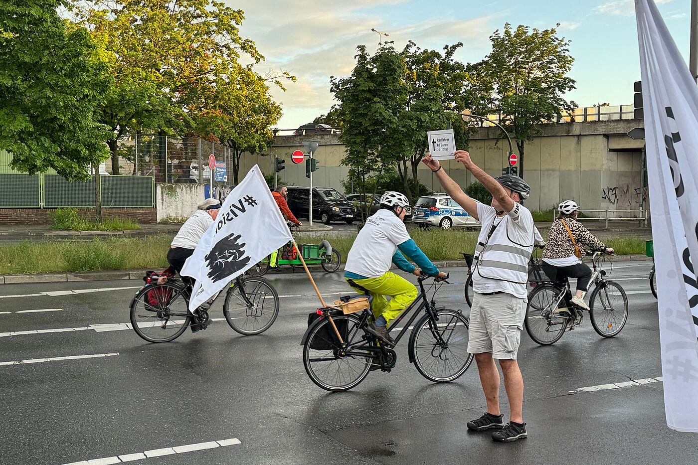 Ride of Silence 2026 Mensch hält bei einer Fahrraddemonstration ein weißes Schild zum Gedenken an 2025 verstorbenen Radfahrer