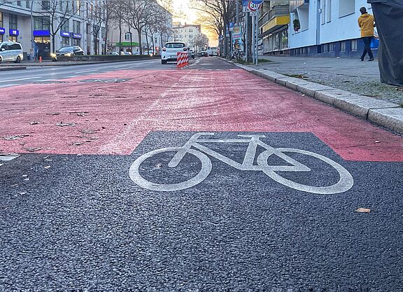 Der Radweg auf der Grundwaldstraße wurde klar vom Autoverkehr getrennt. Auf der Fahrbahn der Grunewaldstraße ist ein geschützter Radweg mit Baken, roten Markierungen und einen Fahrradpiktogramm versehen.