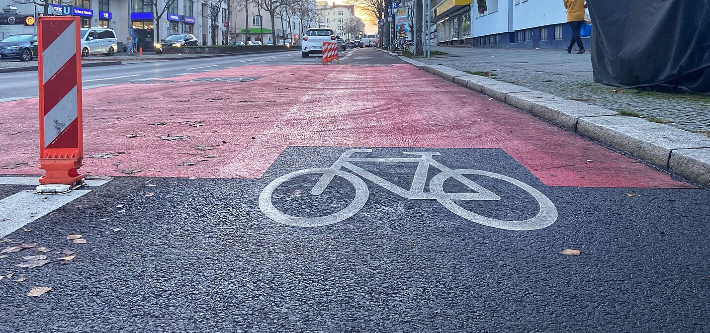 Der Radweg auf der Grundwaldstraße wurde klar vom Autoverkehr getrennt. Auf der Fahrbahn der Grunewaldstraße ist ein geschützter Radweg mit Baken, roten Markierungen und einen Fahrradpiktogramm versehen.