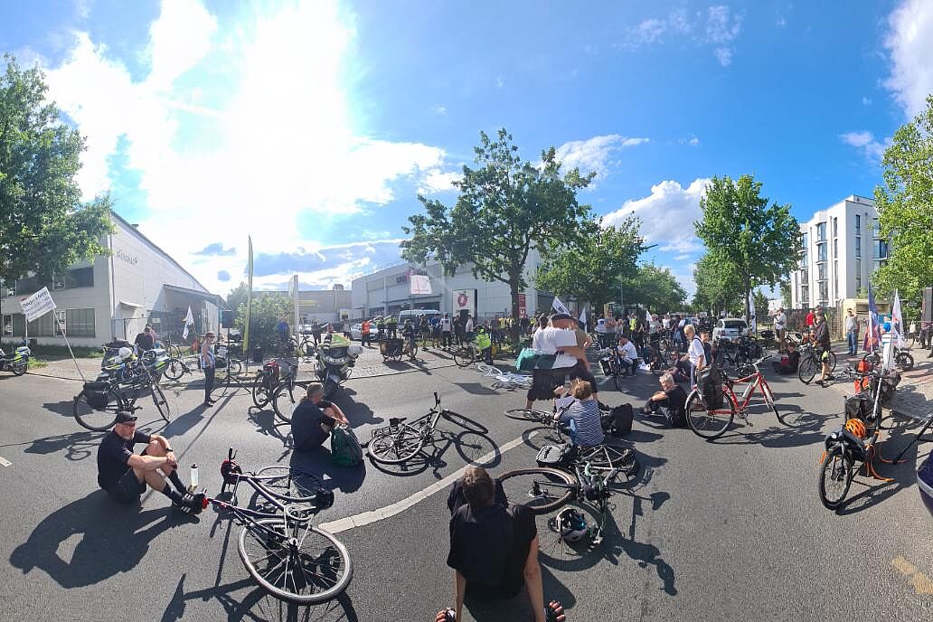 Mahnwache für die getötete Radfahrerin in Marienfelde Menschen sitzen bei einer Mahnwache auf dem Boden um ein weißes Fahrrad