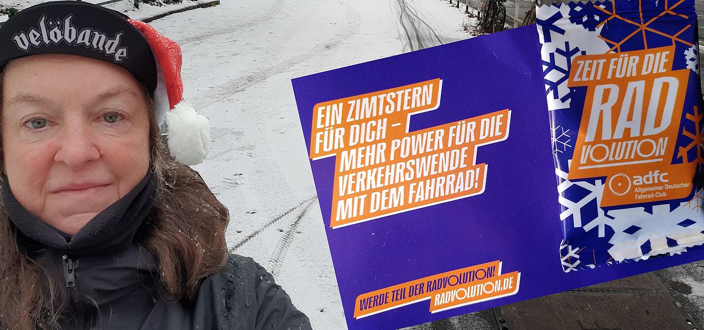 Stadtteilgruppe Mitte - Nikolaus Aktion Die Fotomontage zeigt SuSanne Grittner auf der Seestraße mit einer Postkarte, an der eine lila und weiß bedruckte Plastikverpackung angeheftet ist.