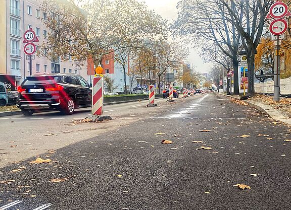 Auf der Grunewaldstraße entsteht ein geschützter Radstreifen Zwischen Martin-Luther-Straße und Bayerischem Platz ist eine frisch asphaltierte Fahrbahn am rechten Rand durch einen weißen Streifen und Baken von der Spur für Autos weiter in der Mitte abgegrenzt.