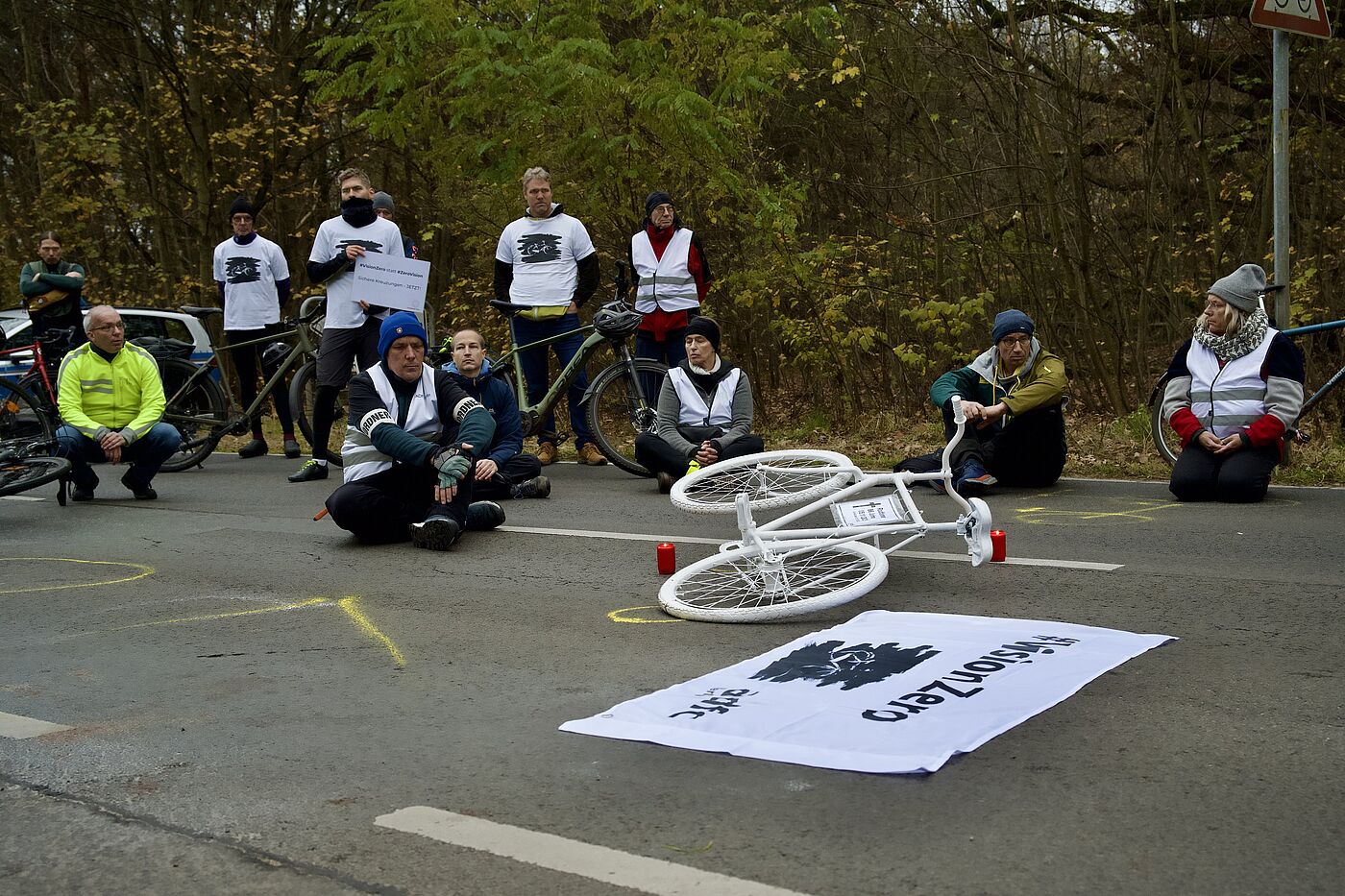 #VisionZero-Demo und Mahnwache für getöteten Radfahrer in Müggelheim Menschen sitzen zur Mahnwache auf der Fahrbahn, in der Mitte liegt ein weißes Geisterrad