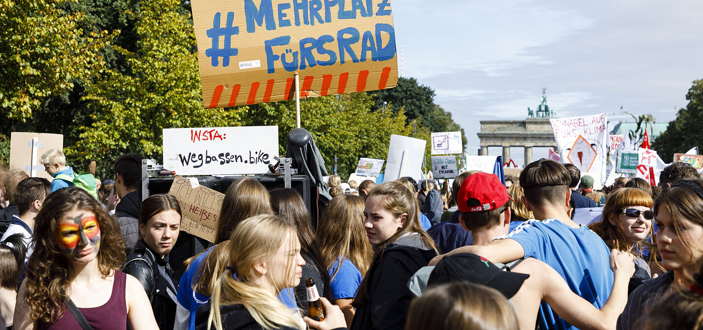 Teilnehmende halten bei einer Demo ein Schild hoch.