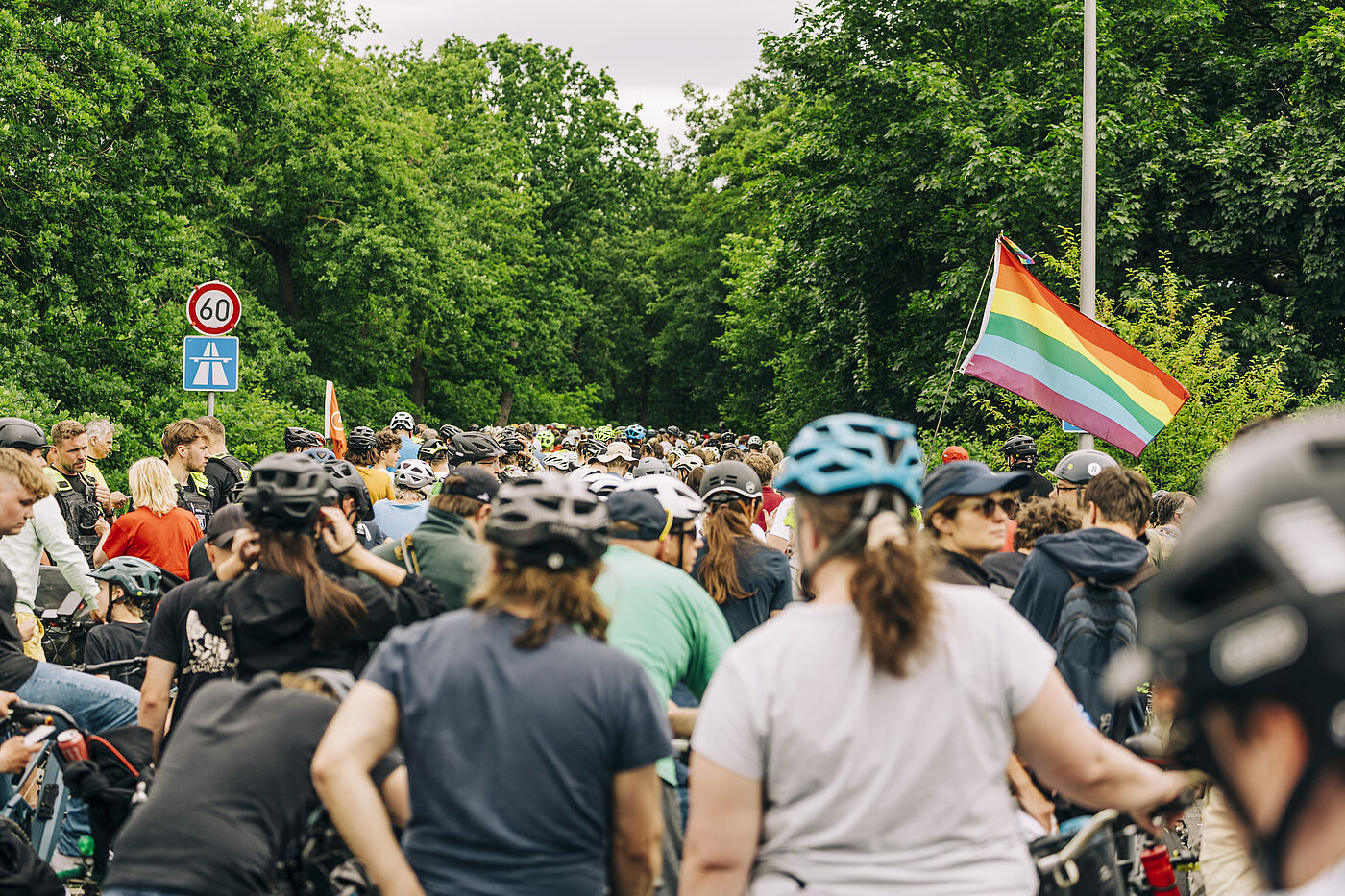 Sternfahrt 2026 Auffahrt Autobahn Radfahrerinnen mit Helm von hinten und eine Regenbogen Fahne