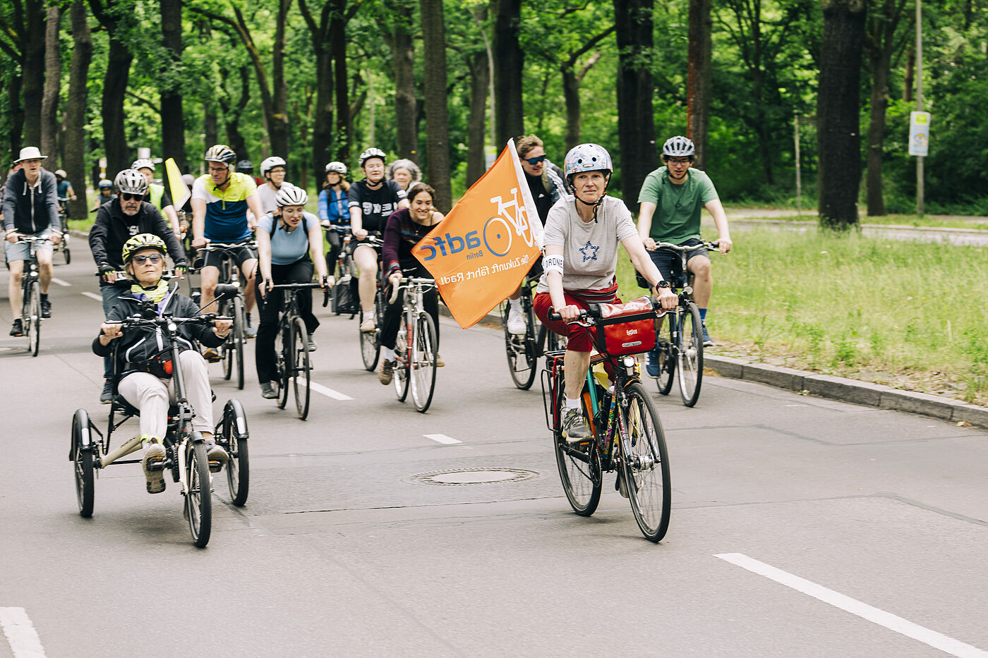 Sternfahrt 2026 Sternfahrt Helferin mit grauem T-Shirt und oranger ADFC Fahne