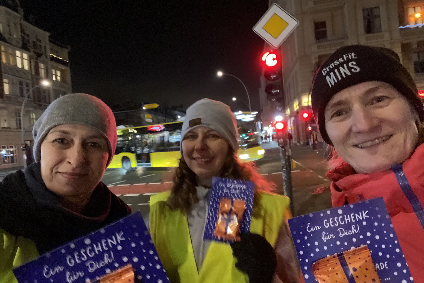 ADFC Lebkuchen-Aktion in Berlin Schöneberg am 17.12.2025 "Selfie" von drei Frauen, die an einer roten Ampel in Berlin Schöneberg stehen, Hauptstraße Ecke Kolonnenstraße. Sie halten Karten des ADFC mit angehefteten Lebkuchen in den Händen.