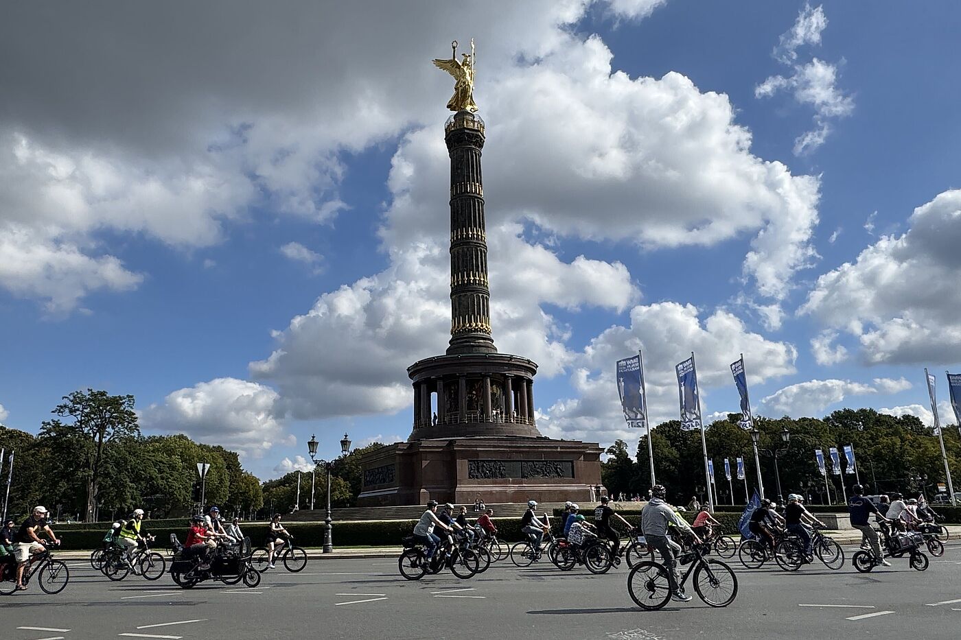 Vor der Siegessäule fahren Radfahrende. 