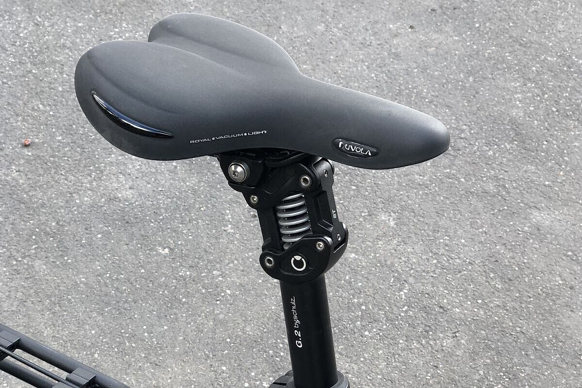 Nahaufnahme einer gefederten Sattelstütze mit sichtbarer Stahlfeder in einer Parallelogrammkonstruktion. 