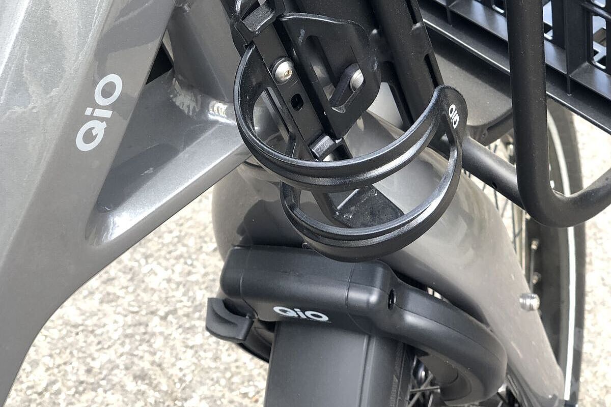 Nahaufnahme des Steuerrohrs vom Qio-Kompaktrad mit montiertem Flaschenhalter und dem oberen Teil der Gabel mit Schloss.