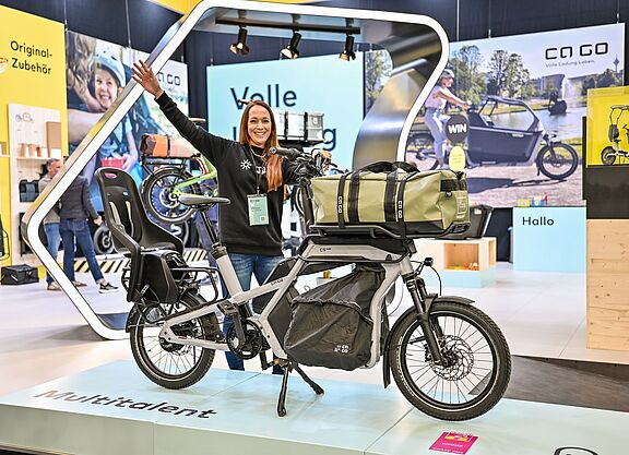 Eurobike Eine Frau steht an einem Messestand und präsentiert ein Lastenrad.